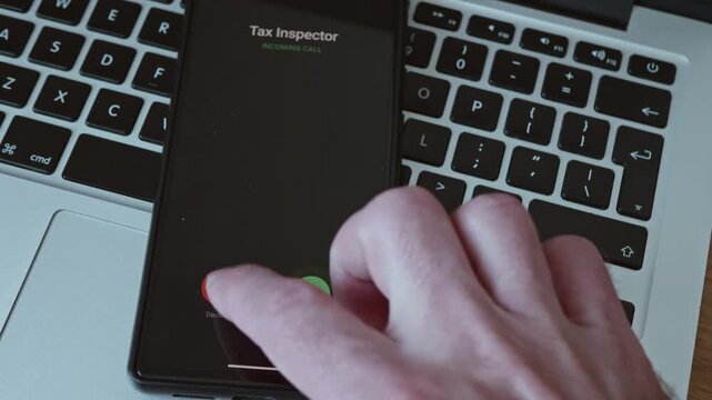 Close-up of a hand declining an incoming call from a Tax Inspector on a smartphone screen.