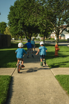 Boys rollerblading and biking on a suburban sidewalk