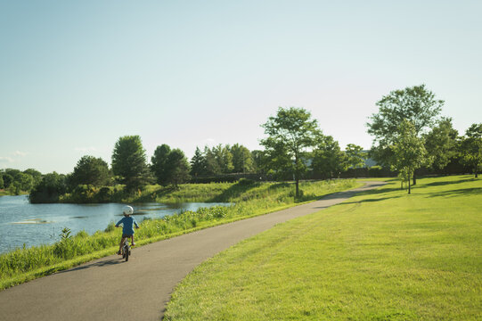 Young boy rides his bicycle on a park path with copy space