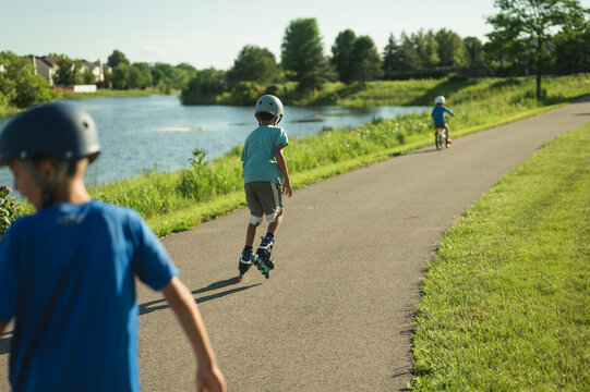 Young boys rollerblading on a path by a lake