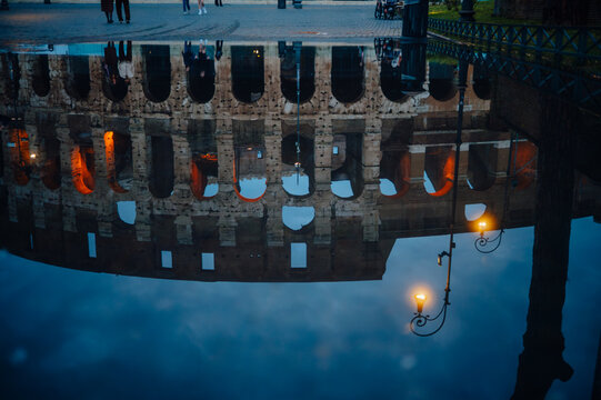 Roman Colosseum reflected in a puddle at dusk