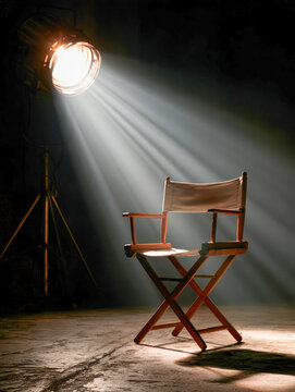 Wooden Director's Chair Under Dramatic Spotlight on a Dark Stage with Cinematic Theater Lighting