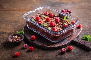 Plakat Decadent chocolate raspberry brownie baked in glass dish, topped with nuts and mint