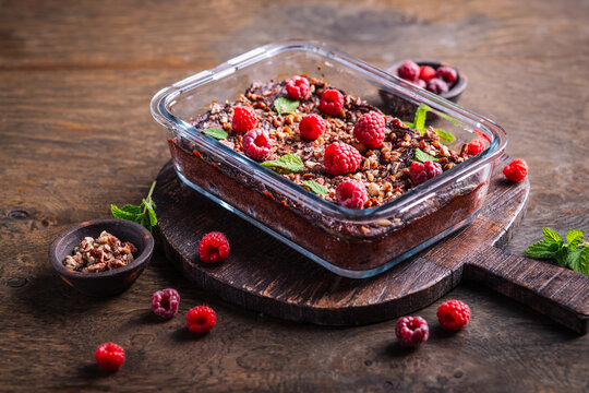 Decadent chocolate raspberry brownie baked in glass dish, topped with nuts and mint