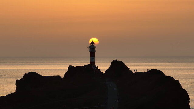 Tenerife, Canary Islands: Warm orange sunset over the Atlantic Ocean with Punta de Teno Lighthouse standing on the rocky cliffs of Tenerife Island in the Canary Islands, Spain. Drone flight