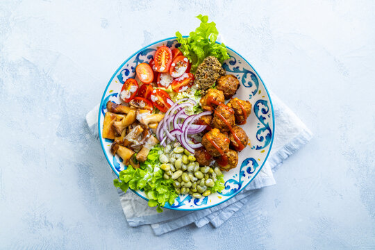 Hearty and healthy bowl with meatballs, mushrooms, beans, and fresh vegetables