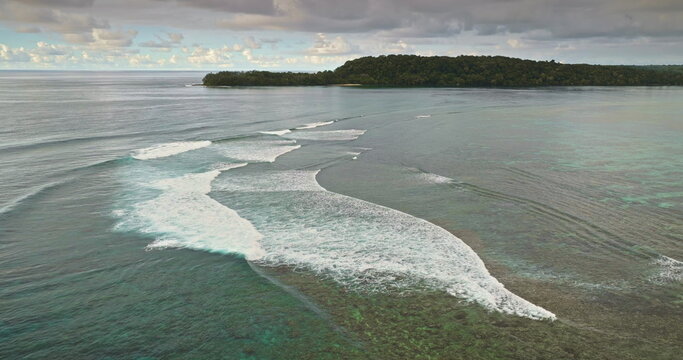 Tropical Solomon Islands landscape. Clear turquoise ocean water with waves breaking over a vibrant coral reef in the South Pacific Ocean. Nature peaceful background. Aerial drone view static shot