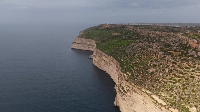 In Dingli Cliffs on Malta's coast, the rugged high cliffs rise above the Mediterranean Sea with rocky outcrops and sparse vegetation visible in an aerial view.
