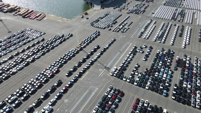 Top down drone pan shows car rows, a loading ramp, and a moving vehicle.