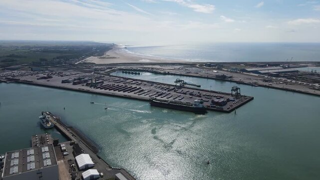 Drone view shows an ocean tanker unloading while small sailboats enter the port.
