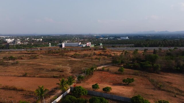 Field with Bengaluru to mysuru expressway, palm trees, vehicles and sky at Vajarahalli village, bengaluru, karnataka, india. day time, push in shot, drone shot, 4k.