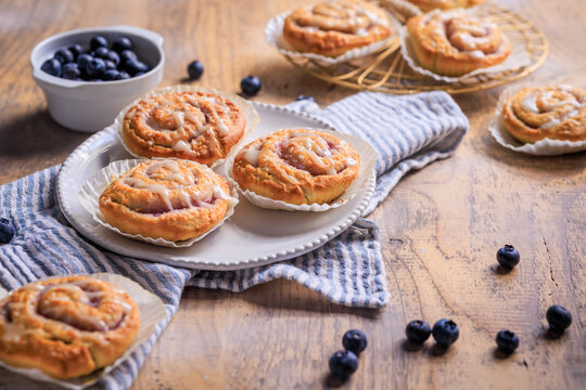 Delicious blueberry cinnamon rolls with sweet icing on a rustic wooden table