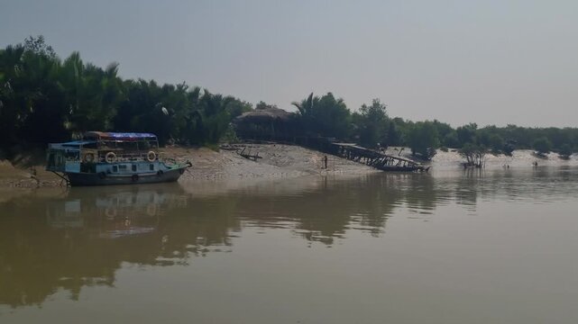 POV from a boat moving through a river in the Sundarbans, revealing muddy shores at low tide and silhouettes of local people fishing during the receding water, capturing everyday life in Bangladesh