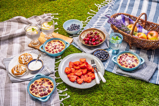 Delicious summer picnic spread with fresh fruits and baked treats on green grass