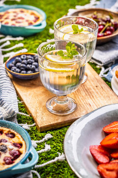Delicious summer picnic spread with fresh fruits and baked treats on green grass