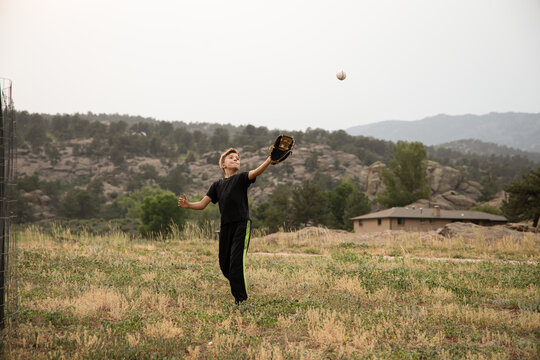 Boy playing catch in field in the mountains