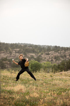 Boy throwing baseball in the mountains