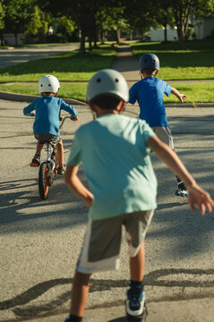 Three young boys biking and skating on quiet neighborhood street