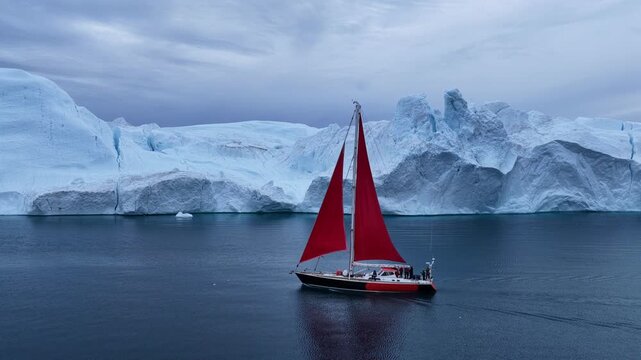 Red sailboat explores a majestic icy landscape