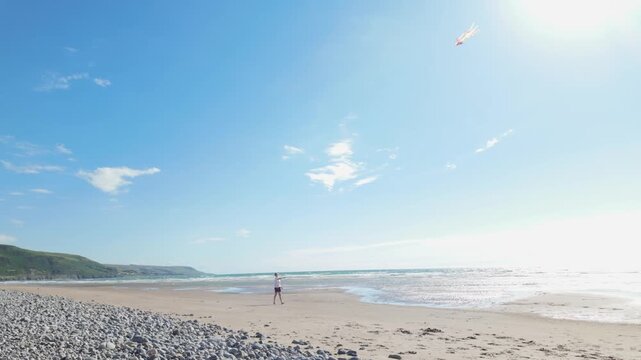 Teen boy flying a colorful kite on a sandy beach