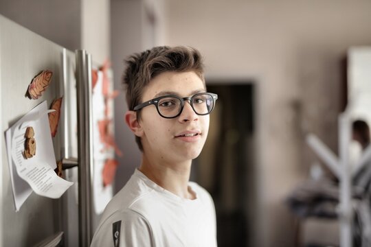 Candid portrait of teen boy with glasses at home
