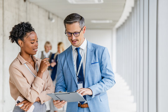 Business colleagues discussing documents in office corridor during professional meeting