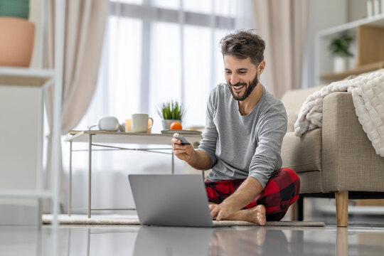 Caucasian man shopping online at home with laptop and credit card in cozy living room