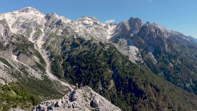 Albania showcases the serene beauty of Valbona Pass, where majestic mountains meet vibrant greenery. A couple walking in the Albanian Alps near Theth