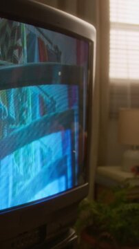Vertical of African American teenage girl lying on bed, experimenting with creative video effects with vintage camcorder and old CRT television. Nostalgic youth marketing or retro technology campaigns