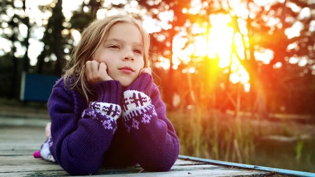 Little girl lies on river pier