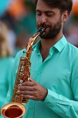 Fototapeta premium Bearded male saxophonist in turquoise shirt playing saxophone for music banner and performance background