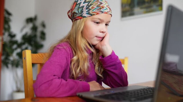 Little blonde girl working on laptop