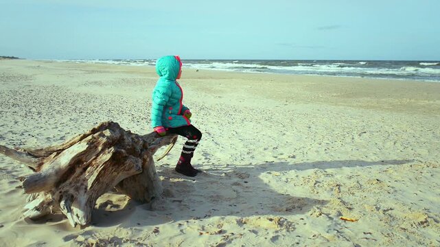 Little beautiful sad girl sits about sea