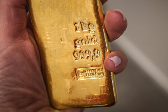 Gold bullion kilo bar in hand. Large cast investment gold ingot. Business and finance.