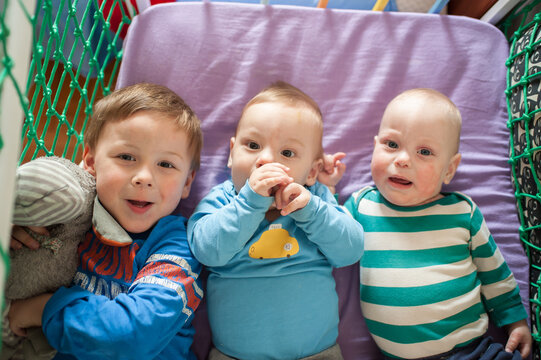 Brothers and little ones nestled together in a vibrant playpen, their innocent eyes reflecting pure, unbridled childhood delight