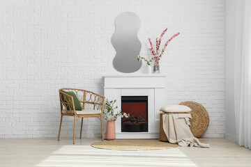 Fototapeta premium Interior of living room with fireplace, armchair and blooming branches in vases