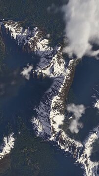 Aerial view of snow-capped mountain ridge above forested slopes