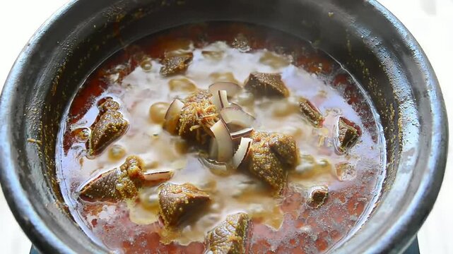 Overhead Shot of Steaming Clay Pot Filled with Traditional Beef Rendang Featuring Tender Meat and Rich Sauce for Culinary Use