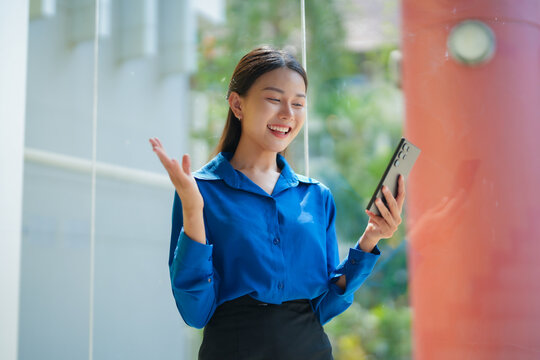 Asian businesswoman feeling happy and holding smartphone in office