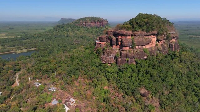 Drone shot capturing the seven levels of hand-built wooden staircases surrounding a massive sacred rock formation in the jungle