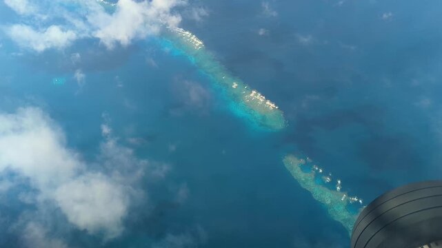 Flying above tropical ocean with blue and turquoise water and coral reefs in outer islands of Fiji, South Pacific