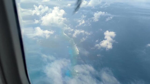 View from airplane window flying over blue ocean and coral reefs in outer tropical islands of Fiji, South Pacific