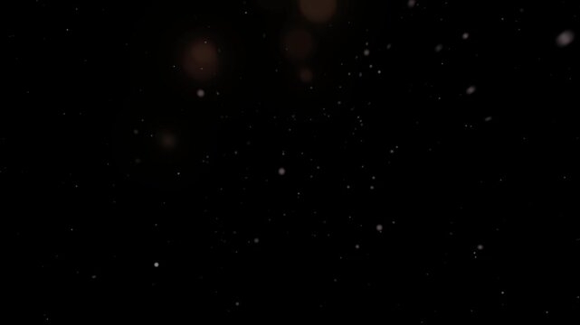 Dust particles drift through a dark environment as soft out-of-focus orbs of light hover in the distance.