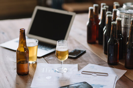 Beer bottles, glasses, documents and laptop on table