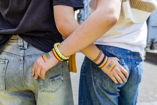 Rear view of crossed arms with rainbow paint at pride parade