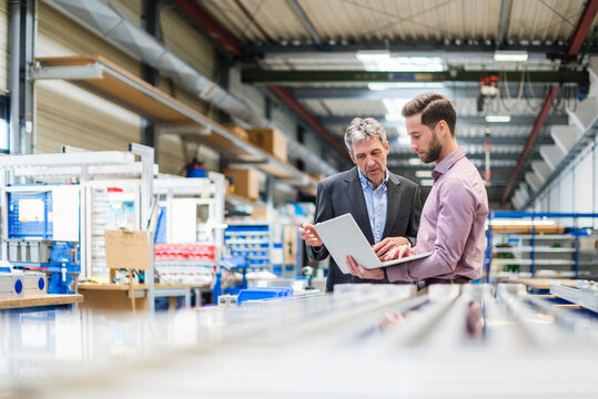 Businessmen using laptop in production hall