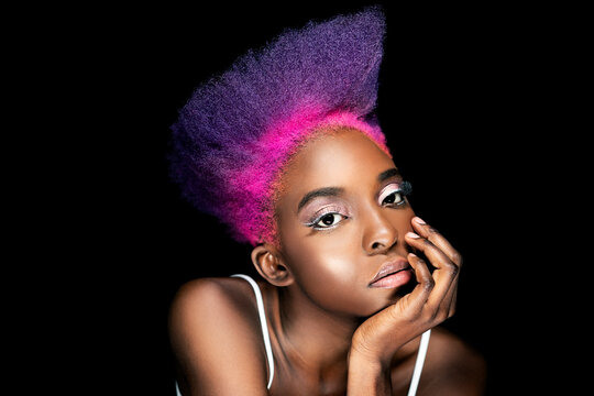 Portrait of eccentric young woman with pink and purple dyed hair in front of black background