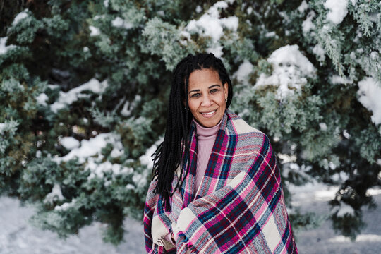Hispanic woman wrapped in shawl at park during winter