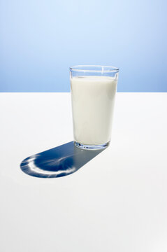 Glass of fresh milk on a white table against a blue background