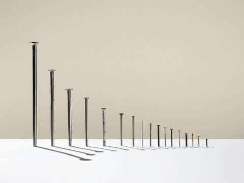 Row of metal nails arranged as a graph showing comparison